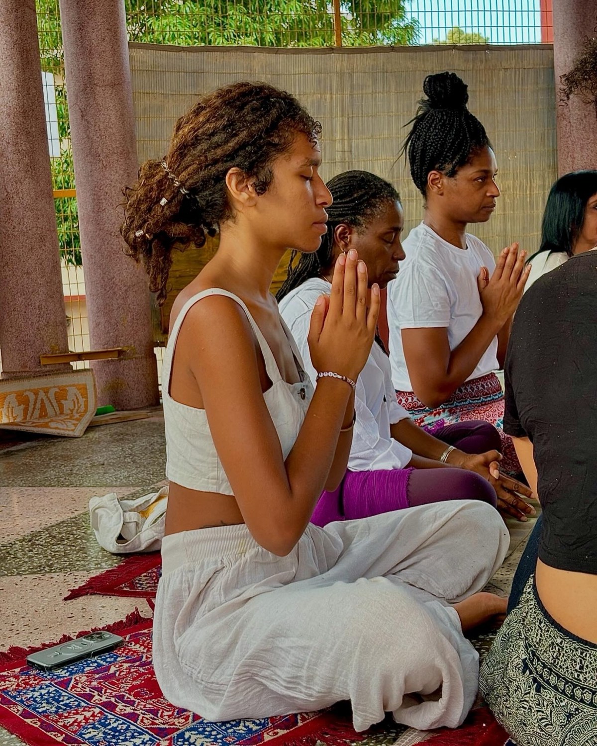 Community members seated together with hands in prayer during shared practice